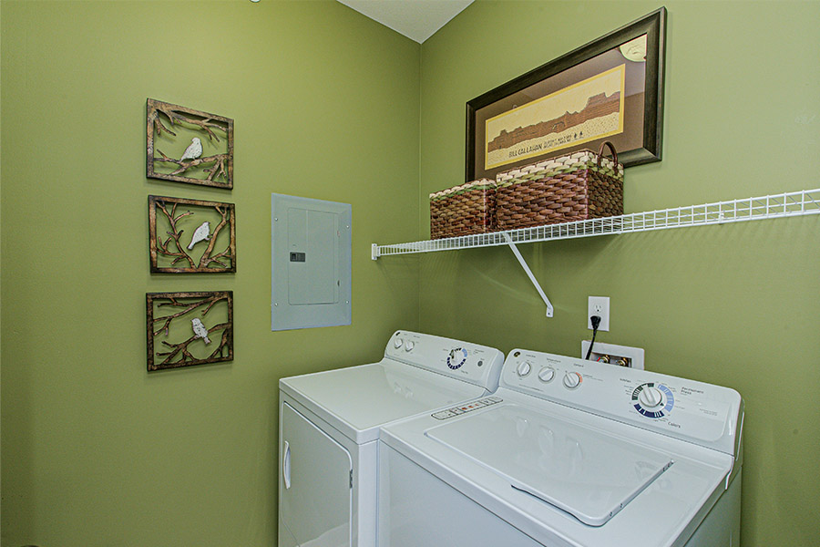 Green laundry room with shelving storage located at Ivy Flats Apartments.